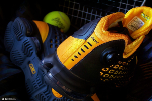 Ein Schuhpaar und ein Ball befinden sich in der Mitte des Bildes, im Hintergrund ist ein Zaun zu sehen.