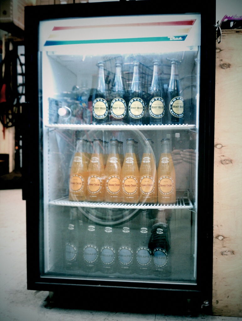 Ein Mini-Kühlschrank mit Flaschen, die Etiketten tragen, vor einem unscharfen Hintergrund.