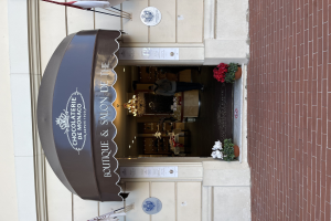 Ein Boutique- und Salon namens "Boutique & Salon de Monaco" mit Außenbereich, Topfpflanzen und beleuchteter Inneneinrichtung.