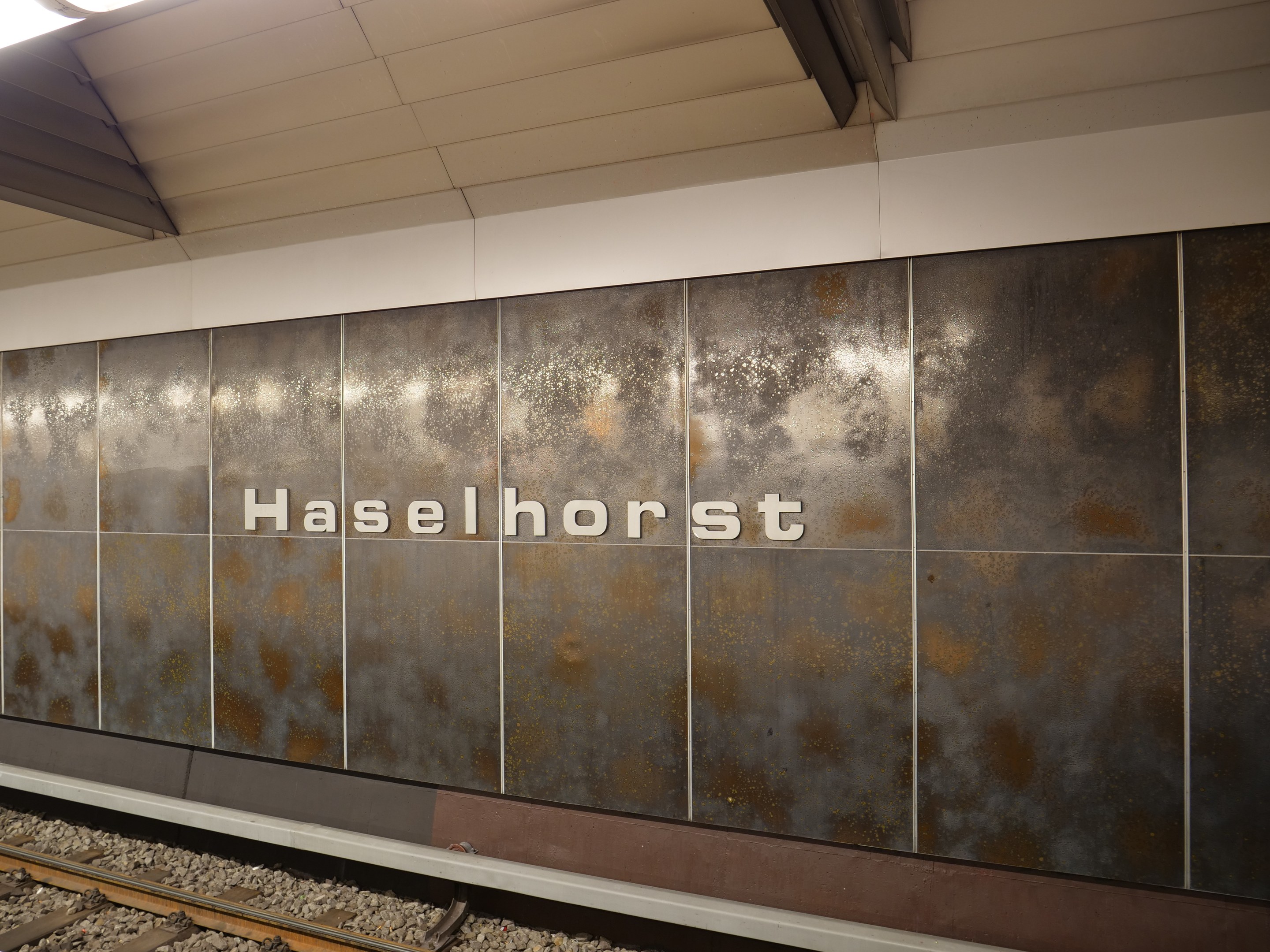 Exterior view of a Berlin train station platform with a "Haselhorst" sign illuminated on the wall.