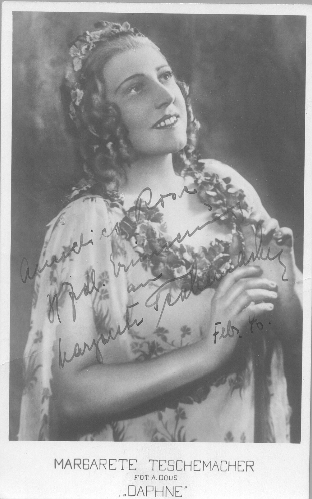 Ein Schwarz-Weiß-Foto einer Frau mit warmem Lächeln, die ein Kleid trägt und ihr Haar in einem 1940er-Look frisiert hat, mit leuchtenden Augen und leicht geöffneten Lippen.