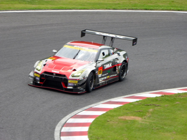 Ein Nissan GT-R Nismo GT3-Rennwagen auf der Nürburgring 24 Stunden-Strecke, mit grünem Gras auf beiden Seiten der Strecke.