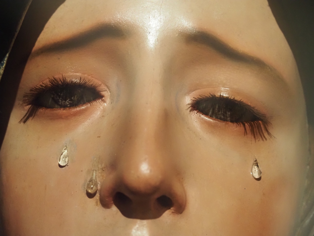 Eine Frau mit Tränen auf den Wangen, ihr Gesichtsausdruck äussert Trauer.