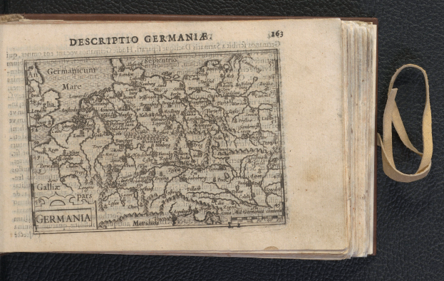 Ein offenes Buch auf einer schwarzen Oberfläche, das eine Deutschlandkarte und Text zeigt und historische Informationen über Deutschland bereitstellt.