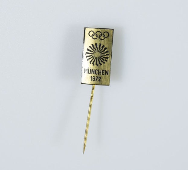 Goldnadel mit "München 1972 Olympische Spiele"-Text auf weißem Hintergrund.