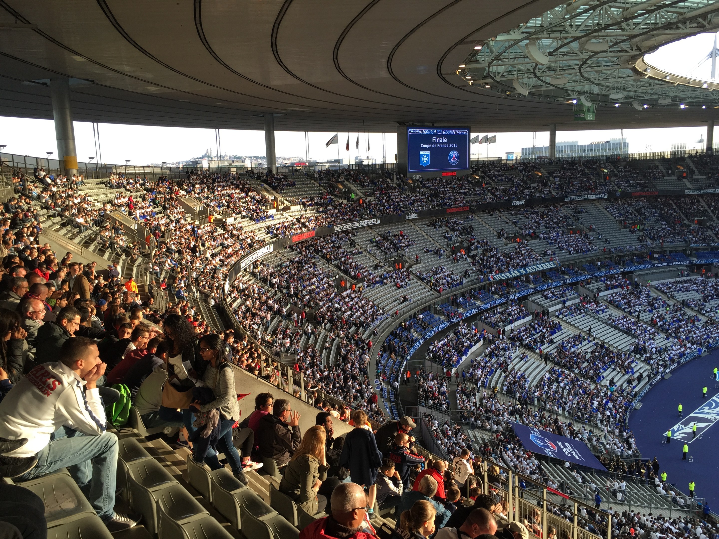 Großes Publikum in einem Stadion bei einem Fußballspiel mit einer Bühne, Fahnen und einem Bildschirm; Allianz Arena in München, Deutschland.
