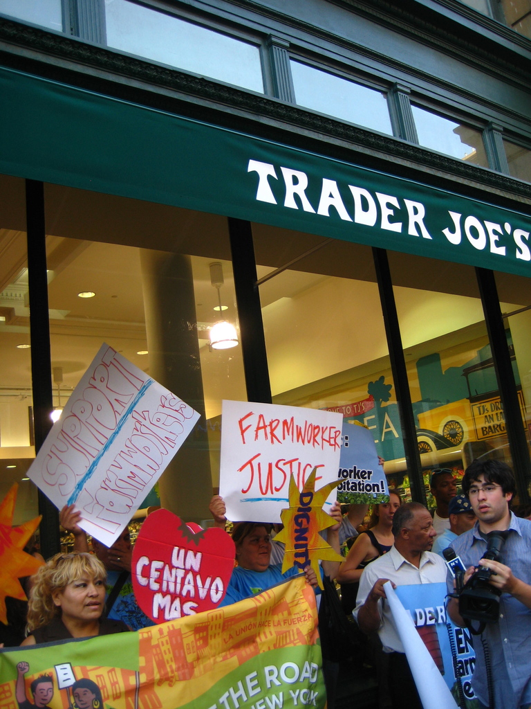 Eine Gruppe von Menschen steht vor einem Geschäft und hält Schilder und Plakate in den Händen.