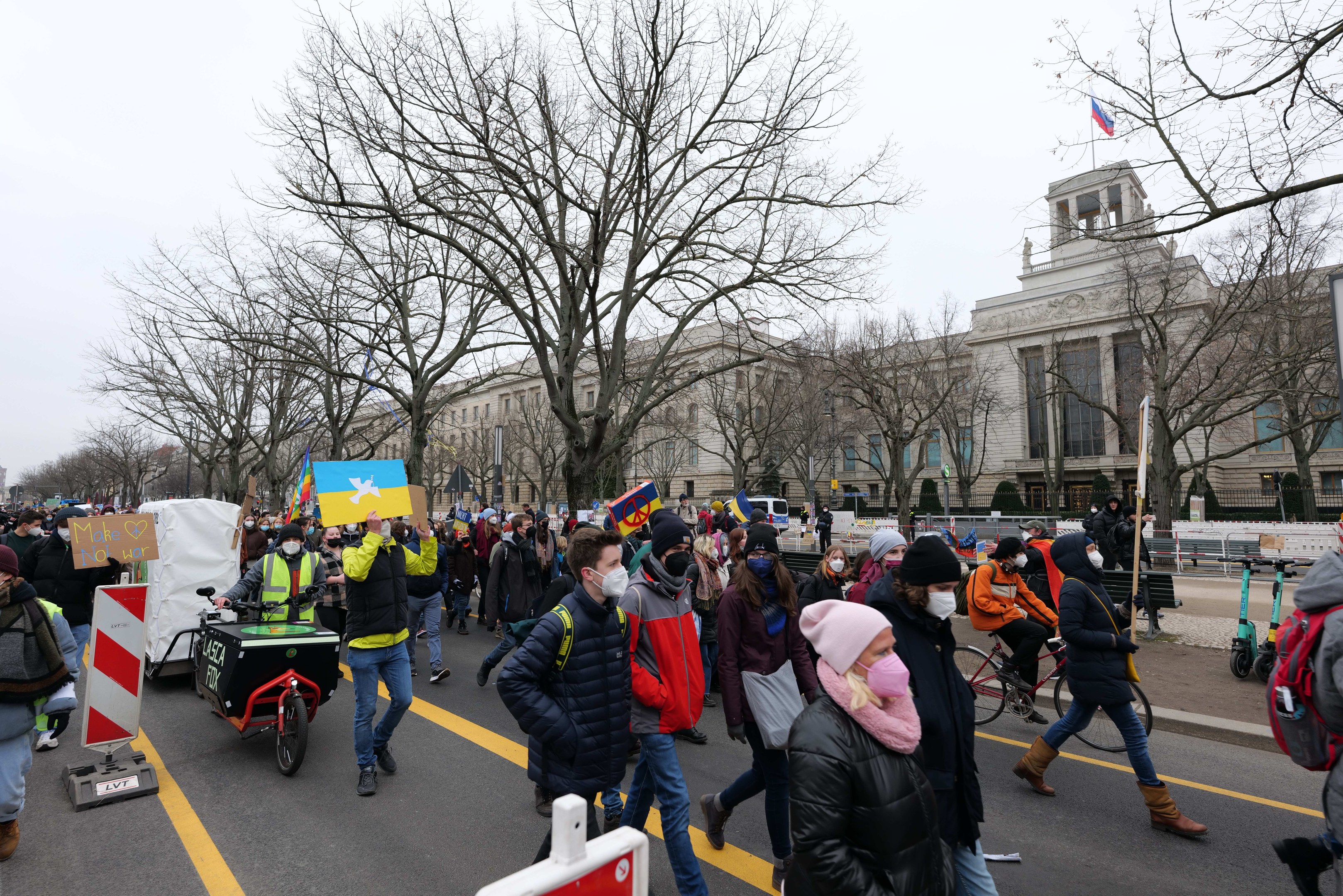 Eine große Gruppe von Menschen marschiert auf einer Stadtstraße bei einer Demonstration, einige halten Schilder und andere fahren Fahrräder, mit Bäumen und einem Gebäude im Hintergrund unter einem klaren blauen Himmel in Washington, D.C. am 21. Januar 2020.