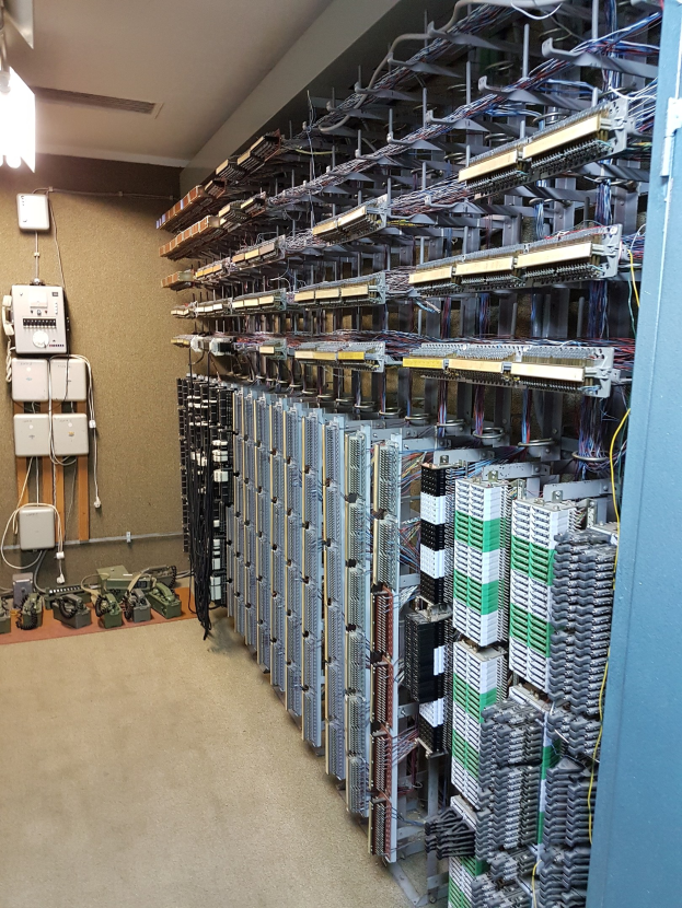 Großer Raum voller Server, Kabel und elektronischer Geräte, typisch für eine Rechenzentrumsanlage.