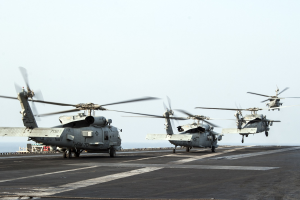 Militärhubschrauber auf dem Deck eines Flugzeugträgers, fliegend über das Meer mit dem Himmel im Hintergrund.