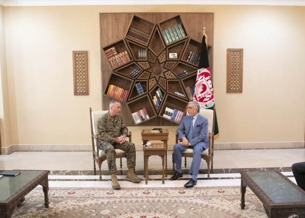 Two men in a room with books and a flag on the wall, engaged in conversation, with one identified as the US Secretary of Defense and the other as the Afghan President.