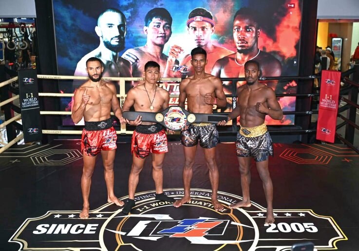 Four men in a boxing ring hold championship belts while a "Muay Thai World Championship" screen displays in the background.