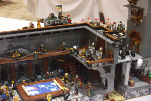 Eine Lego-Königreichszene mit Soldaten, Offizieren und einer Kartendarstellung auf einem Tisch, mit einem weißen Tuch im Hintergrund.