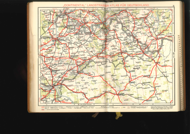 Offenes Buch mit einer detaillierten Karte von Deutschlands Straßen und Autobahnen auf schwarzem Hintergrund.