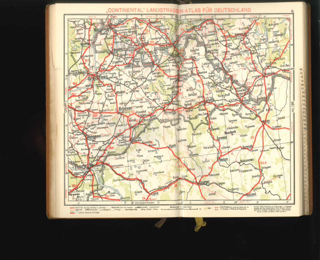Offenes Buch mit einer detaillierten Karte von Deutschlands Straßen und Autobahnen auf schwarzem Hintergrund.