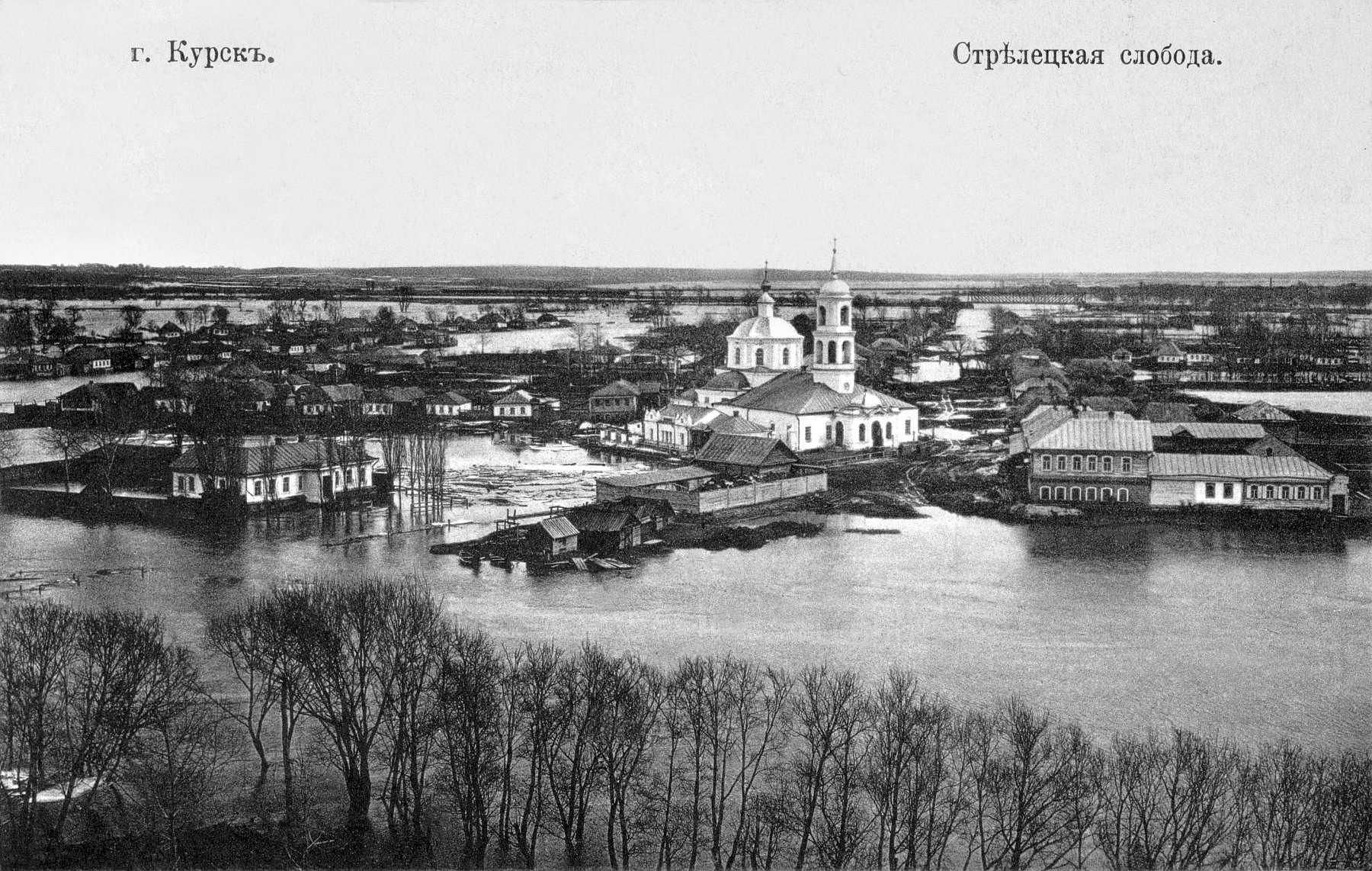 Schwarzes und weißes Foto von Krasnoyarsk, Russland aus dem Jahr 1892, das eine Stadt mit einem Fluss, Bäumen und Gebäuden zeigt.