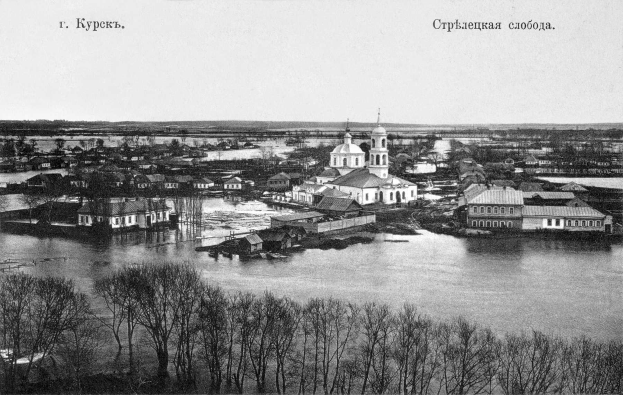 Schwarzes und weißes Foto von Krasnoyarsk, Russland aus dem Jahr 1892, das eine Stadt mit einem Fluss, Bäumen und Gebäuden zeigt.
