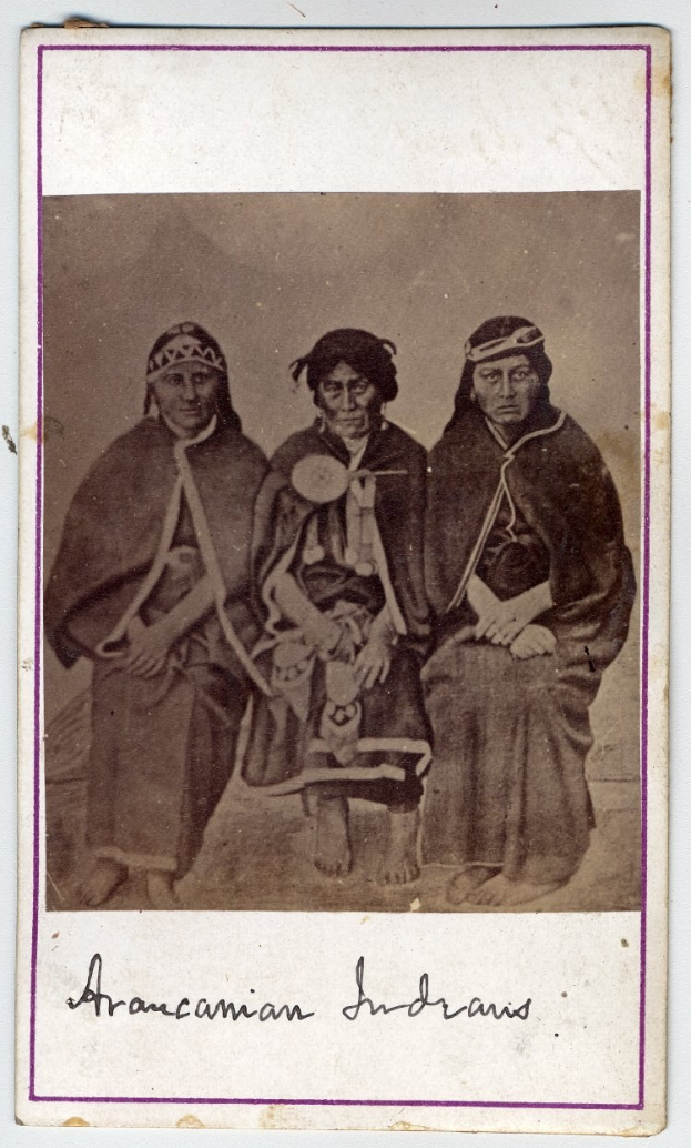 Black and white photo of three Native American individuals seated on a bench with text at the bottom.