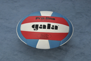 Ein blau-roter Volleyball mit dem Wort "Gala" darauf, der auf einer blauen Oberfläche liegt.