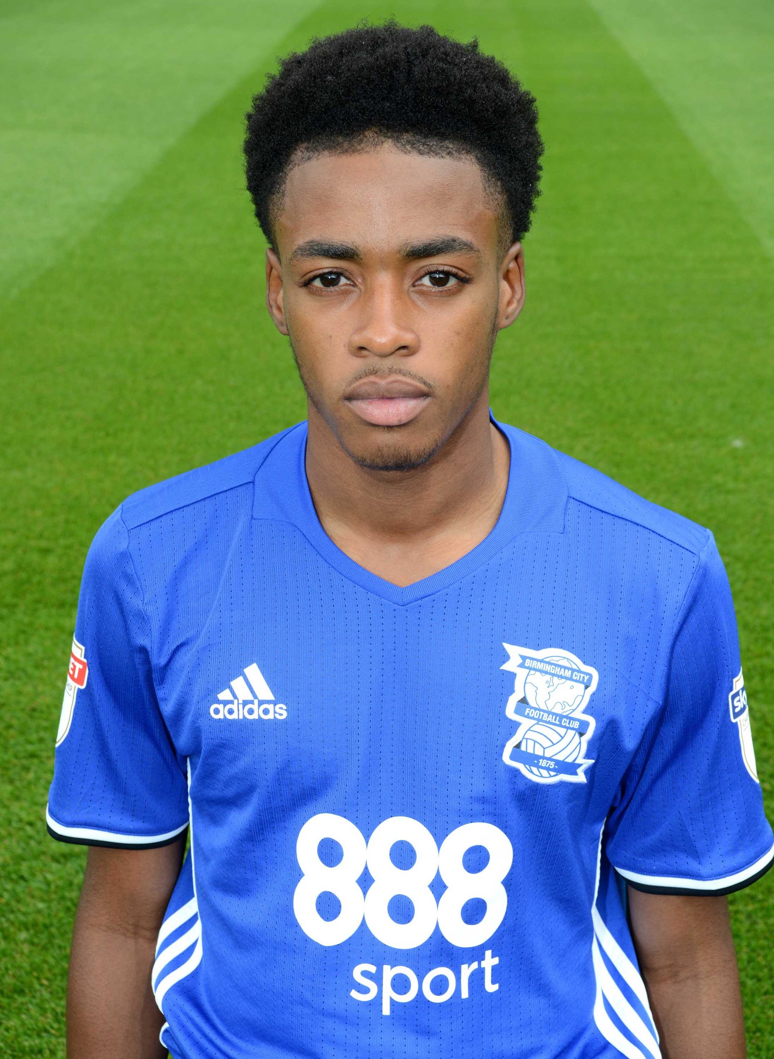 A young man in a blue Everton FC jersey stands on a soccer field in a stadium.