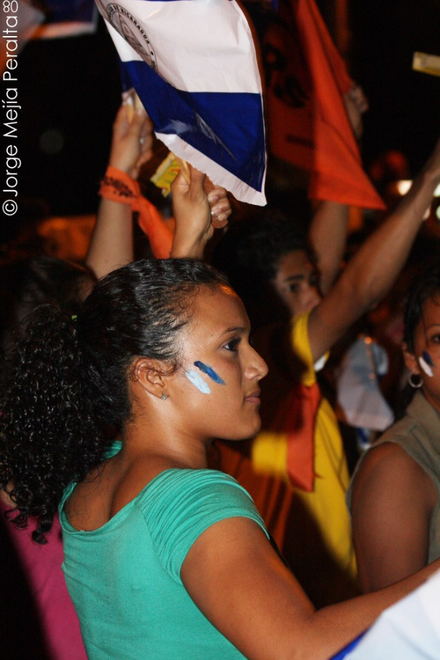 Frauen in grünen T-Shirts, die bei einer Demonstration stehen und weiße Decken halten.