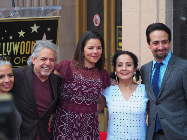 Gruppe von Menschen auf dem roten Teppich bei der Zeremonie des Hollywood Walk of Fame, mit einer Tafel, Glaspodest und Wand im Hintergrund.
