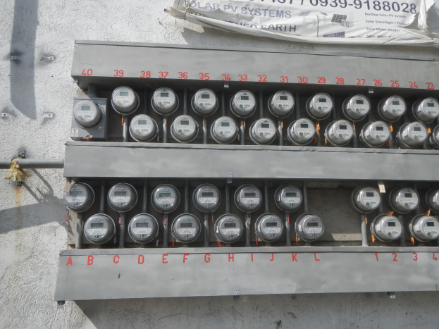 Nahaufnahme eines Stromzählers an der Seite eines Gebäudes mit einem Banner darüber.