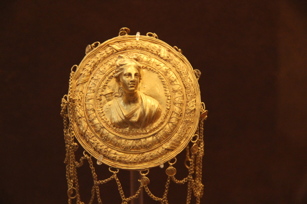 Goldene Medaille mit einer Frauengestalt auf dunklem Hintergrund mit aufwendigen Details.
