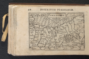 Ein altes Buch mit einer detaillierten Karte von Pommern, das verschiedene Städte und Ortschaften zeigt, auf einer schwarzen Oberfläche.