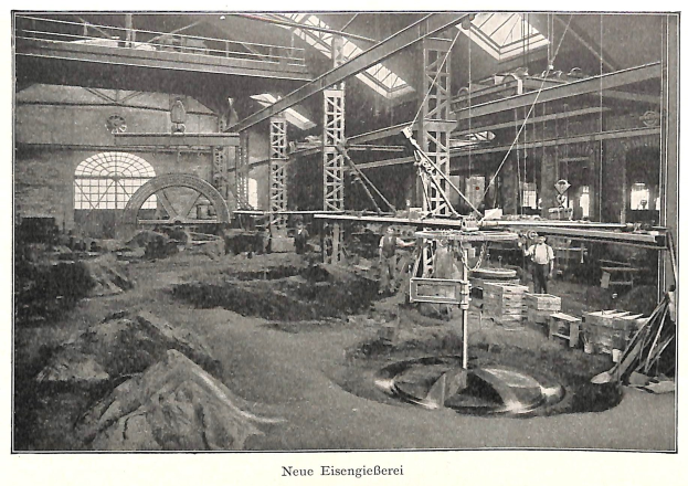 Schwarzes und weißes Foto einer Fabrik mit Arbeitern, die Maschinen bedienen, Metallstangen und -rohre, beschriftet mit 'Neue Eisenglebeerei, die erste Fabrik in Deutschland' unten.