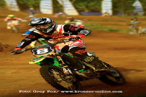 Mehrere Menschen auf Motorrädern bei einem Rennen, alle tragen Helme, mit Text am unteren Bildrand.