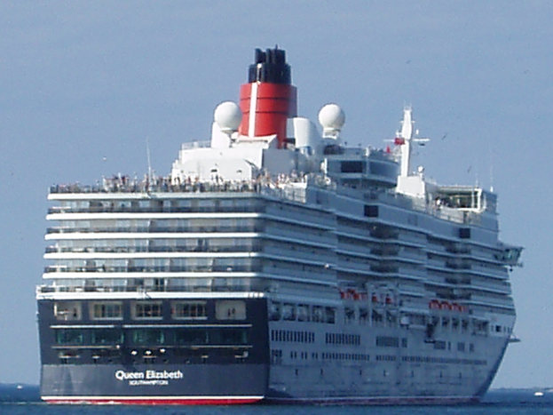 Großes Kreuzfahrtschiff namens Queen Elizabeth segelt auf dem Meer mit anderen Booten im Hintergrund unter einem klaren blauen Himmel.