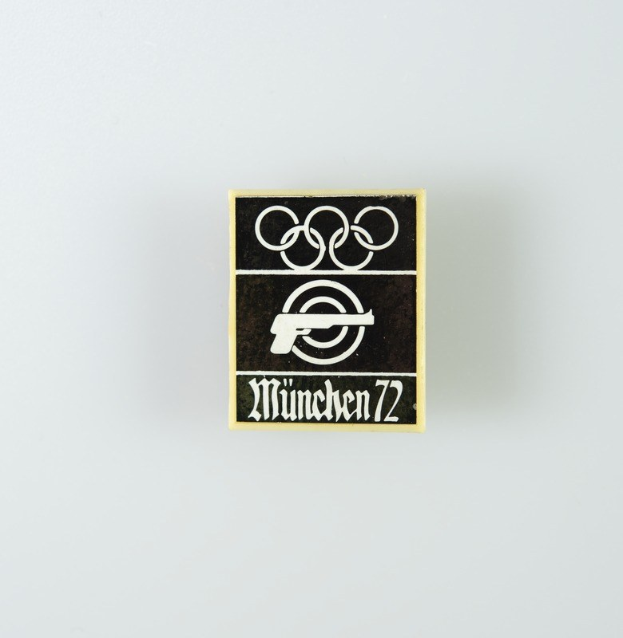 Black and white logo for "München 1972" featuring a circle with a stylized figure and outstretched arms, and bold text in a sans-serif font.