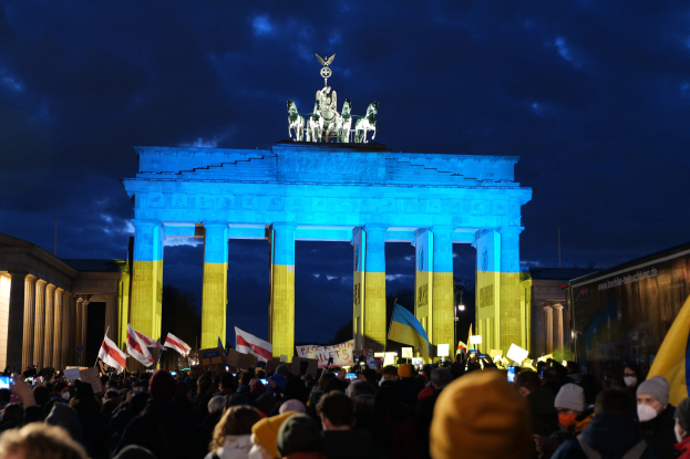 Menge mit Fahnen und Plakaten vor dem Brandenburger Tor, mit einer Fahne auf der rechten Seite des Bildes.