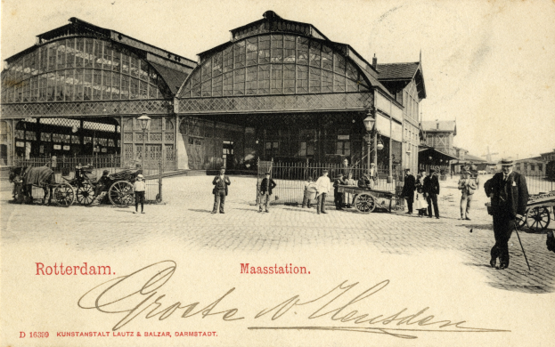 Old postcard of a train station in Rotterdam, Netherlands, showing people with carts, horse carts, street poles, buildings, and a cloudy sky.