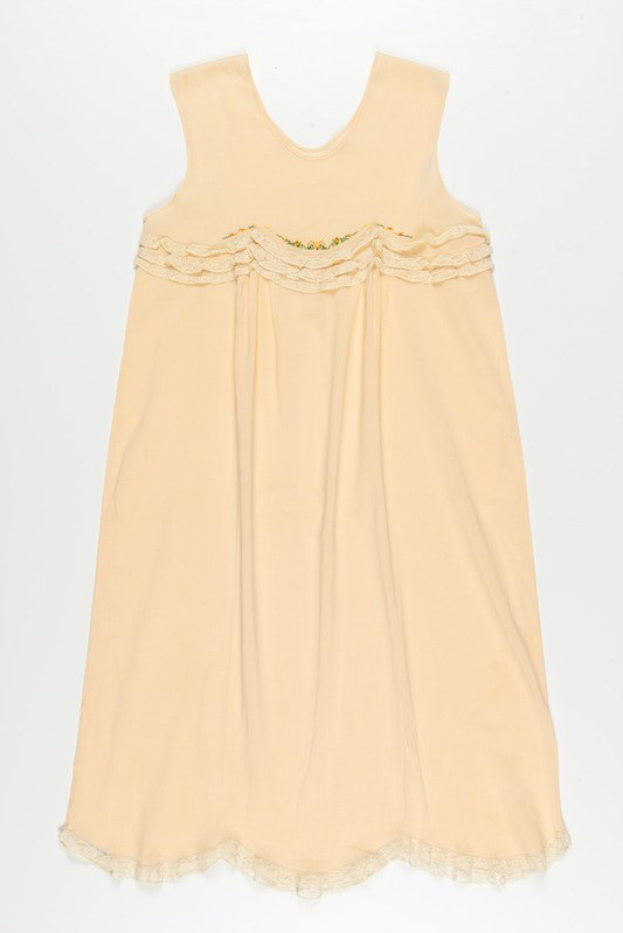 Ein cremefarbenes Nachthemd mit zarter Spitzenverzierung am Halsausschnitt, aus weichem, leichtem Stoff mit einem dezenten Schimmer.