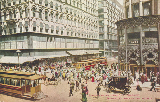 Altes Schwarz-Weiß-Foto einer belebten Stadtstraße mit Passanten, Kutschen und Gebäuden, mit Text am unteren Rand.