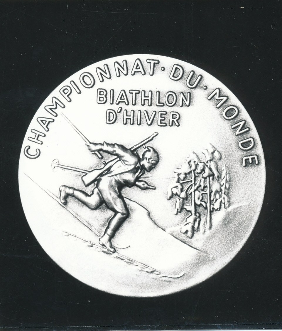 Silberne Medaille mit einer Gravur eines Skiläufers, mit Text, auf schwarzem Hintergrund.