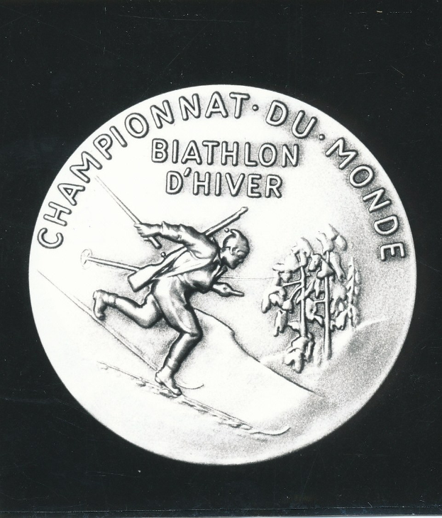 Silberne Medaille mit einer Gravur eines Skiläufers, mit Text, auf schwarzem Hintergrund.
