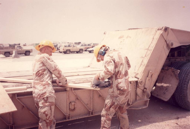 Lkw auf einer Straße mit zwei Männern in Helmen, einer hält ein mechanisches Gerät, und eine Absperrung im Hintergrund.