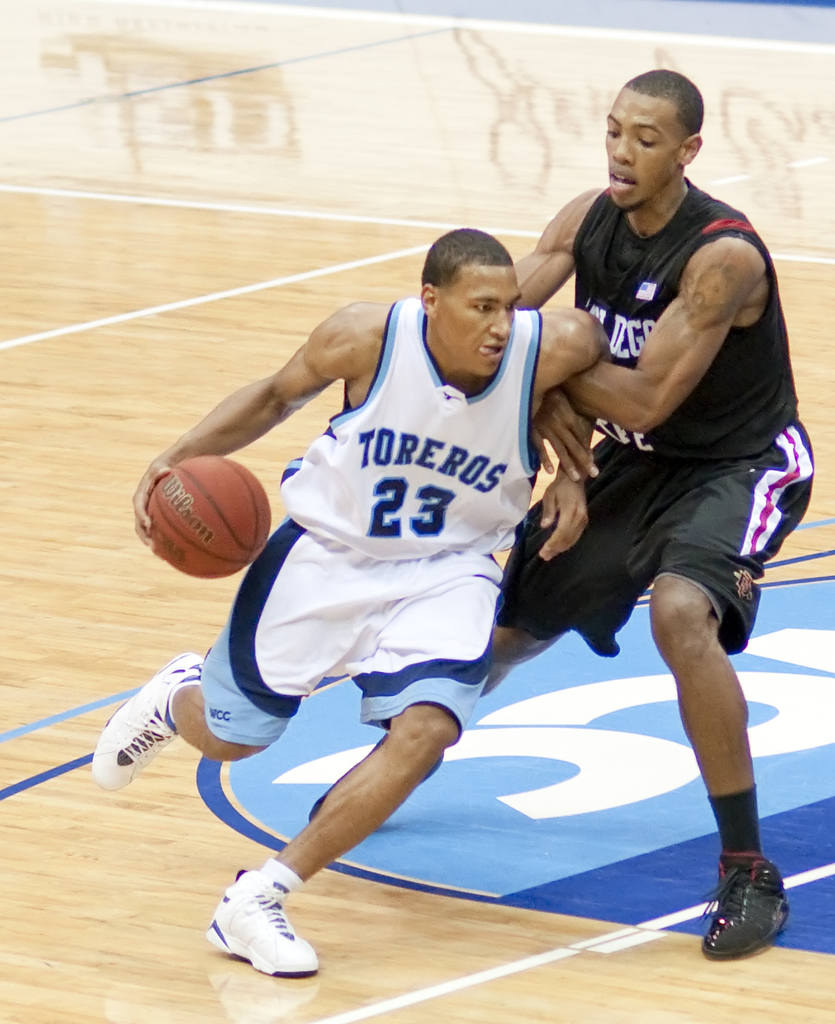 Zwei Personen spielen Basketball, eine hält den Ball in der Mitte.