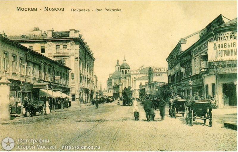 Black and white photo of a Moscow city street with pedestrians, horse carts, buildings, signboards, lampposts, and text at the top and bottom.