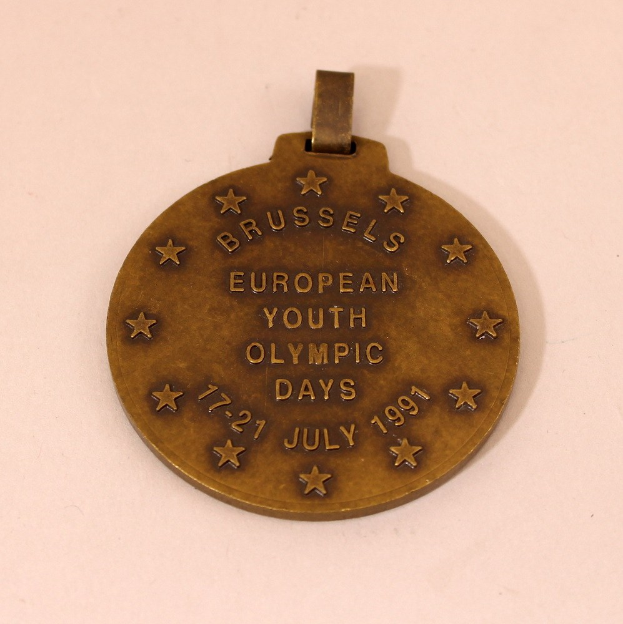 Bronzemedaille mit "Europäische Jugendolympiade" eingraviert, vor weißem Hintergrund dargestellt.