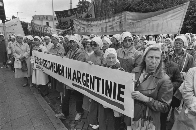 Gruppe von Frauen mit einem Banner 'Argentinischer Frauenmarsch in Argentinien' vor einem Verkehrssignal, Bäumen, Gebäuden und einem bewölkten Himmel