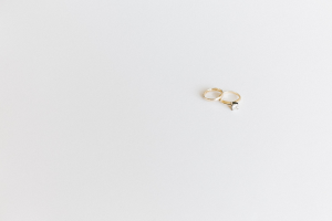 Two gold wedding rings with a single diamond each, set on a white surface, reflecting light.