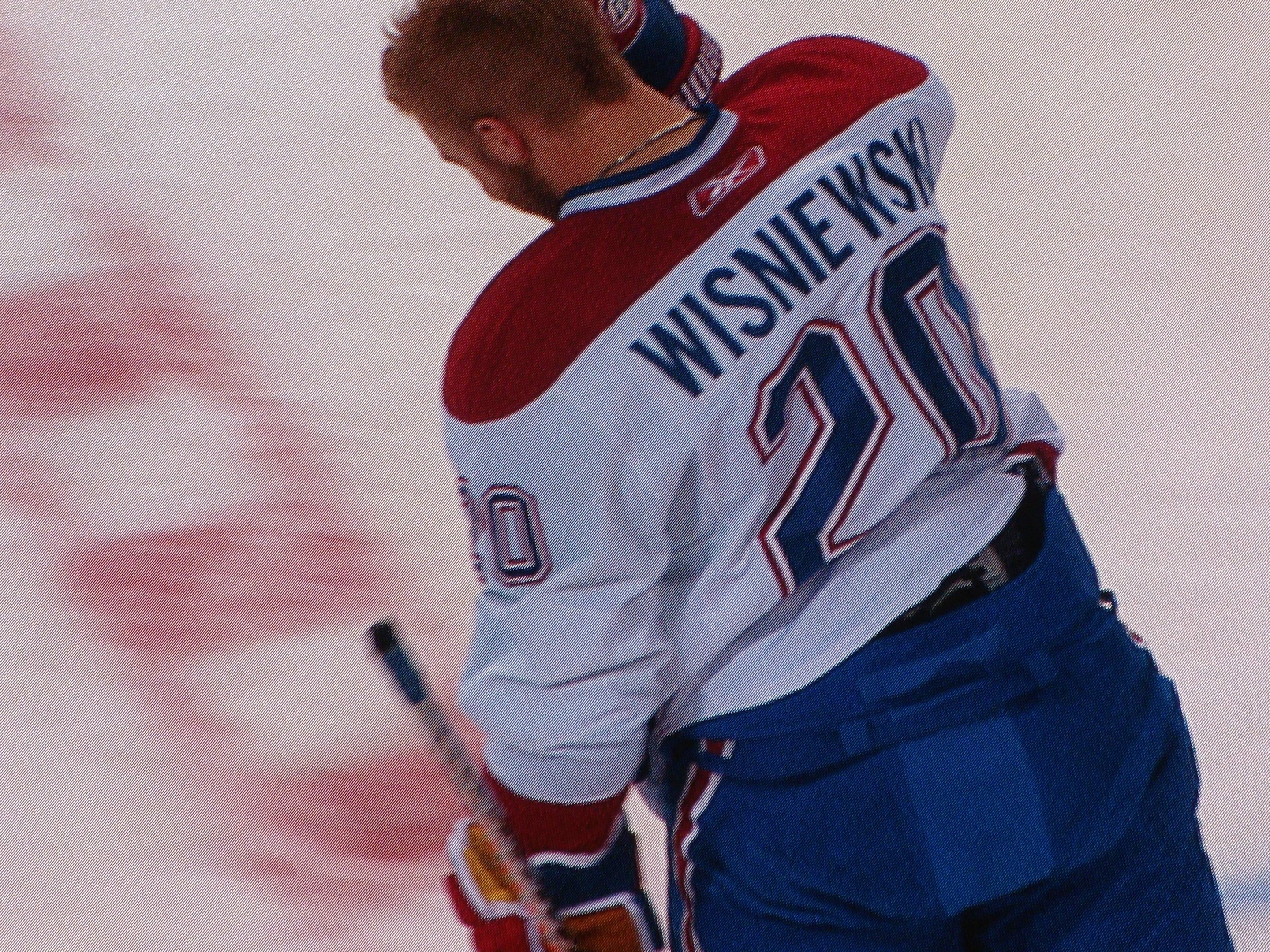 Professioneller Eishockeyspieler in einem "Wisniewski"-Trikot, der einen Hockey-Schläger auf dem Eis hält und konzentriert schaut.