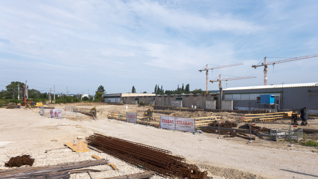 Baustelle mit diverser Ausrüstung, Materialien und Strukturen unter einem bewölkten Himmel.