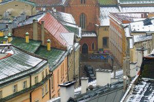 Stadtansicht von einem hohen Standpunkt aus, mit schneebedeckten Gebäuden im Vordergrund und Fahrzeugen auf den Straßen darunter.