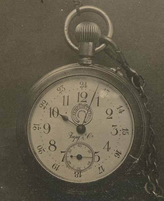 Altes Schwarz-Weiß-Foto einer Taschenuhr mit Kette, mit einer nummerierten Ziffernblättern.