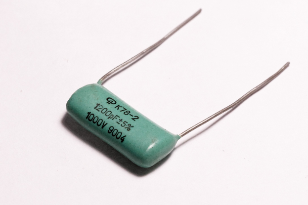 Ein grüner Elektrolytkondensator mit Text auf seiner Oberfläche, der auf einem weißen Tisch steht.